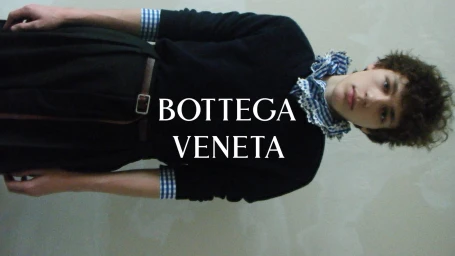 Model wearing a black sweater and blue gingham ruffled collar in the Bottega Veneta Winter 2026 campaign