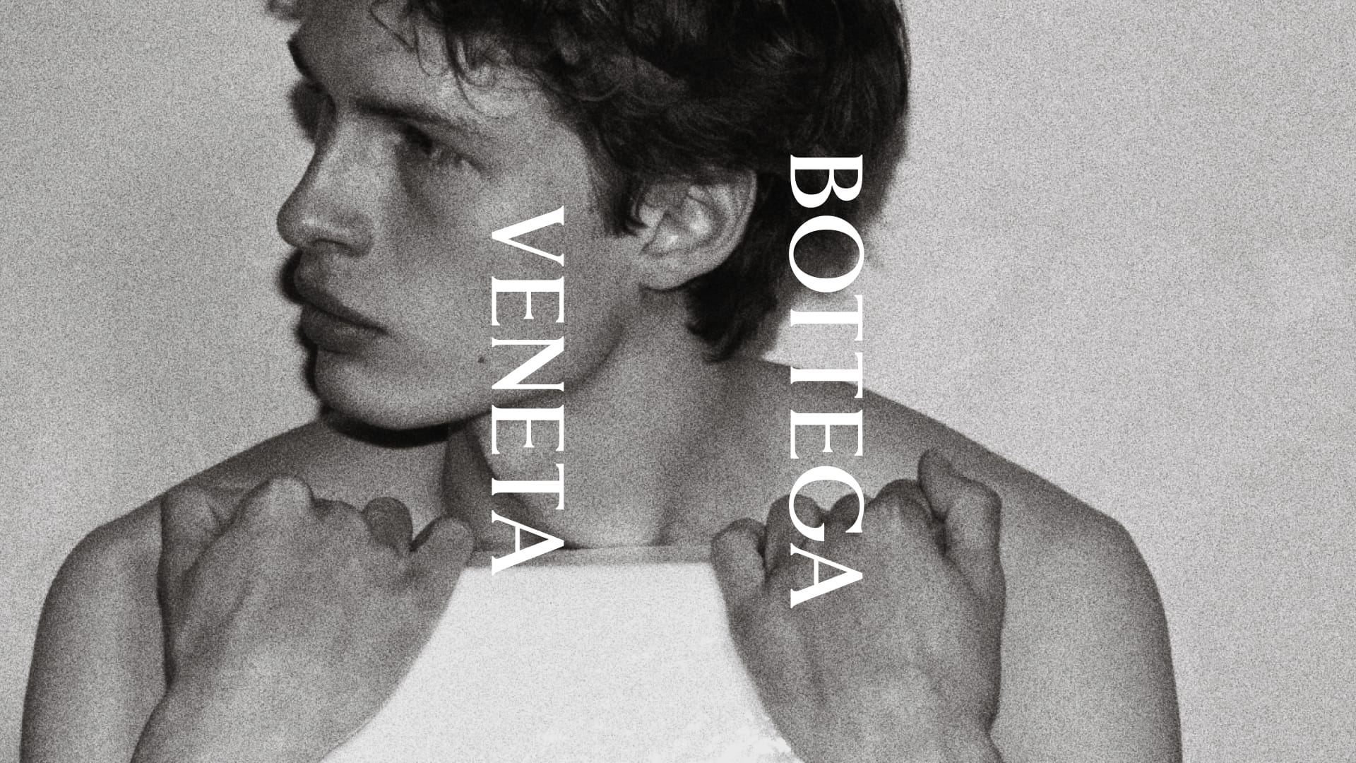 Black and white close-up portrait of a young man looking to the side with vertical Bottega Veneta typography overlay.