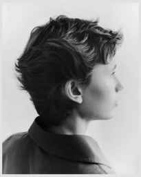 Black and white profile portrait of model Nora Svenson with short textured hair wearing a collared shirt against a light background.