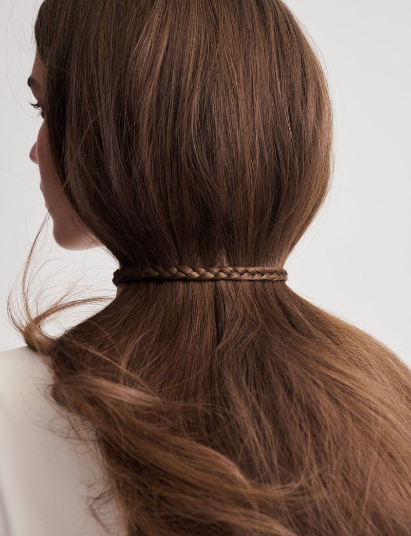 Model Laura Helene Christensen viewed from behind with long brown hair cinched horizontally at the nape with a woven hair braid.