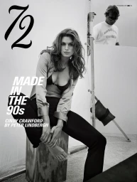 Cindy Crawford seated barefoot on a wooden apple box wearing an open shirt and black bra on an editorial photography set.