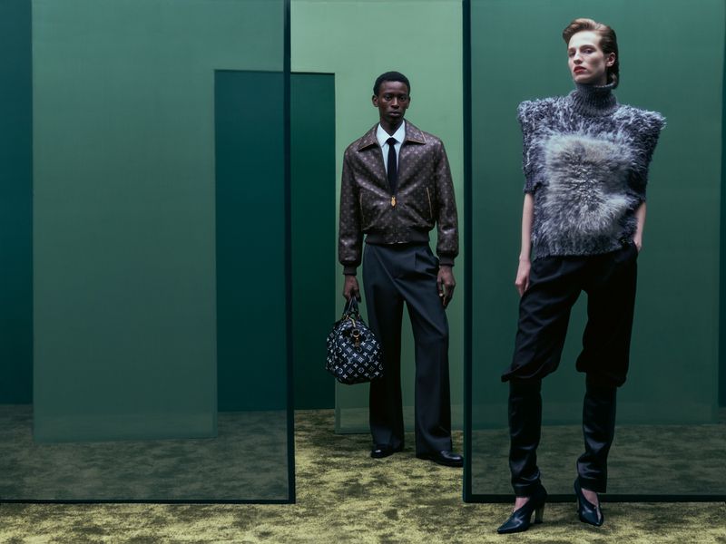 Diana Skowron and Adamu Bulus wearing designer autumn fashion among translucent green architectural glass screens.