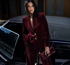 Kendall Jenner in a burgundy velvet suit leaning against a vintage car for Donna Karan