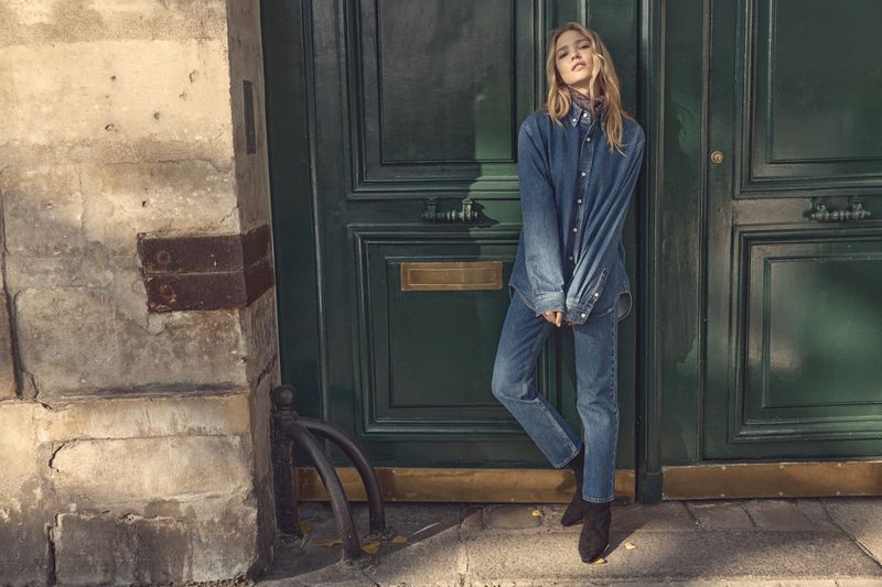 Thea Ros in a head-to-toe denim outfit leaning against a dark green paneled door for the Doen Denim Fall 2026 campaign.