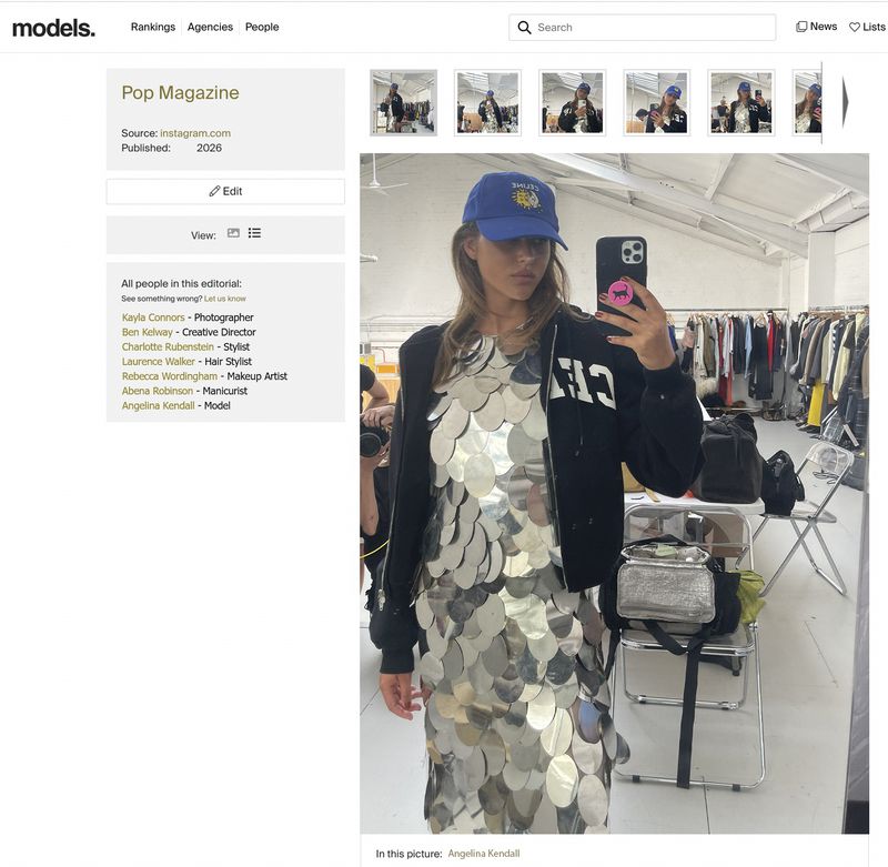 Model Angelina Kendall taking a mirror selfie wearing a blue baseball cap, black jacket, and metallic silver paillette disc dress.