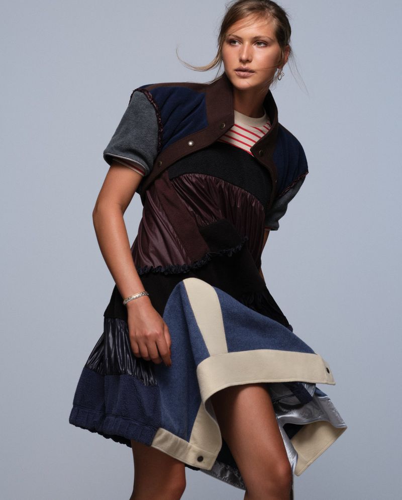 Angelina Kendall wearing a patchwork mixed-media mini dress against a pale grey studio background for Pop Magazine.