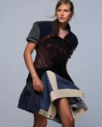 Angelina Kendall wearing a patchwork mixed-media mini dress against a pale grey studio background for Pop Magazine.