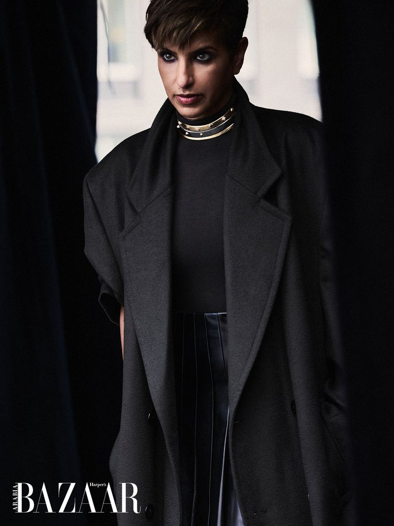 Princess Deena Aljuhani Abdulaziz posing in an oversized black coat and gold choker collar for Harper's Bazaar Arabia.