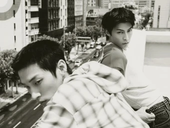 Two men looking from a rooftop ledge over an urban street in a black and white fashion editorial shoot.