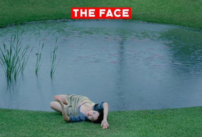 A model lies on the green grass at the edge of a circular pond with reeds for The Face China.