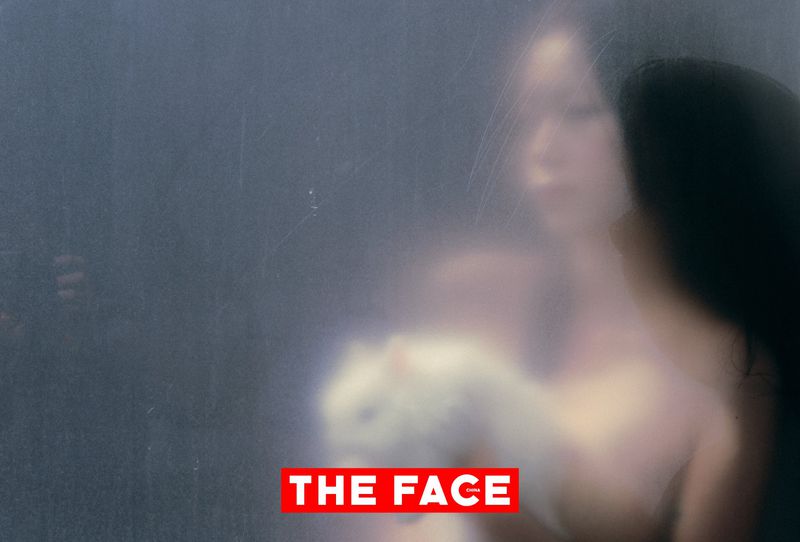 Diffused portrait of an East Asian model holding a white cat behind frosted translucent glass for The Face China.