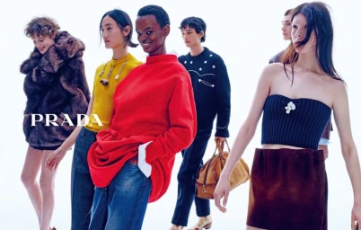 Group of fashion models walking against a bright white studio backdrop wearing red knitwear, yellow top, and fur coat.