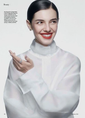 Model Carla Rey wearing a sheer high-neck white blouse and bold red lipstick against a bright studio background.