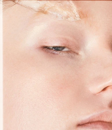 Macro beauty close-up of a fair-skinned woman's eye and eyebrow with clear cosmetic gel applied above the brow.