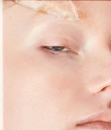 Macro beauty close-up of a fair-skinned woman's eye and eyebrow with clear cosmetic gel applied above the brow.
