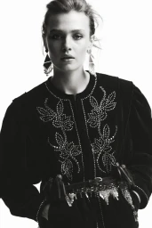 Black and white portrait of a female model wearing an embroidered jacket and statement earrings