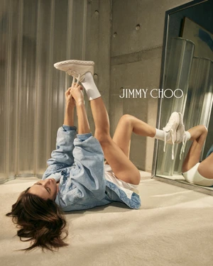 Model Devon Lee Carlson lying on the floor holding white sneakers for Jimmy Choo Wardrobe Collection 2026