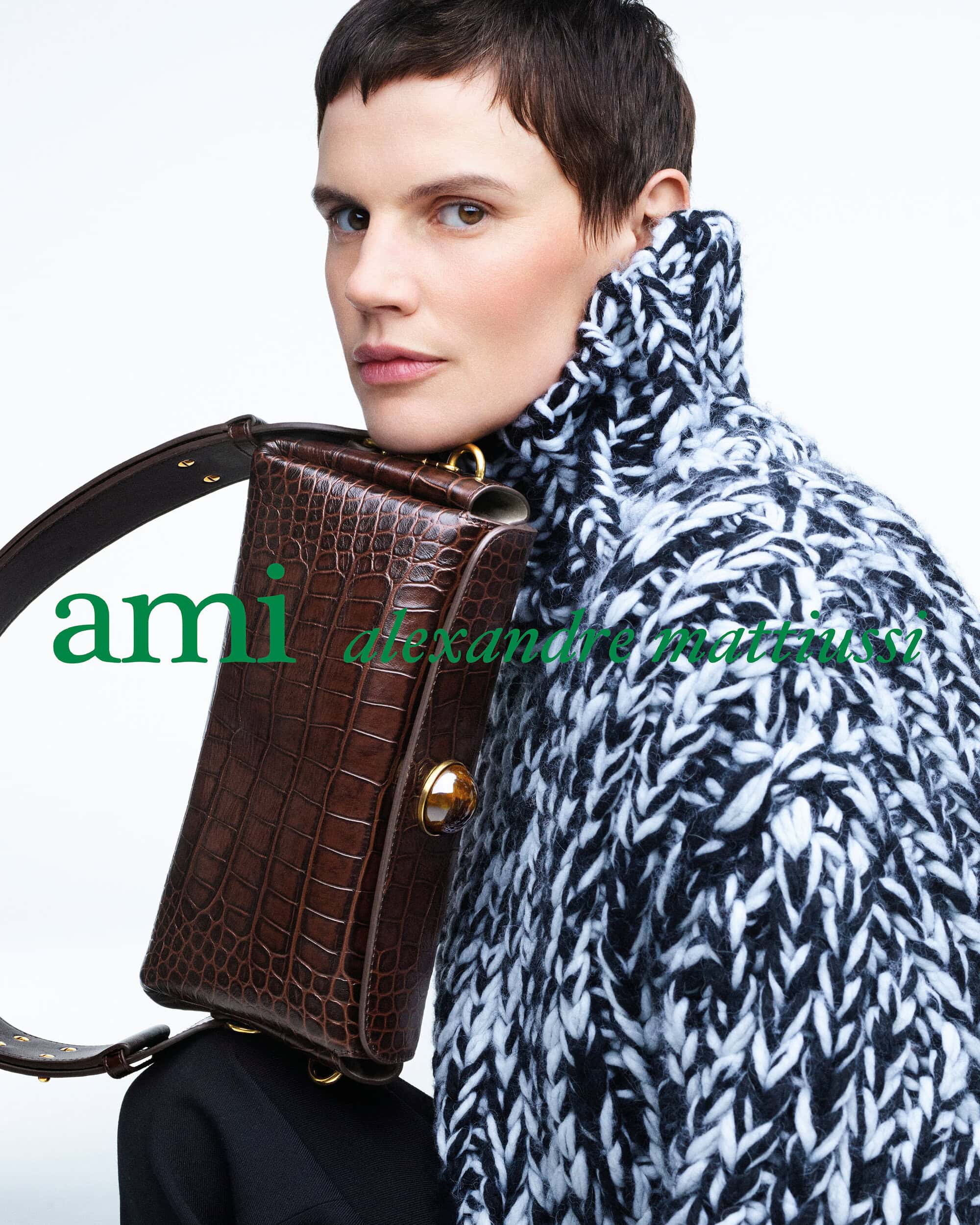 Model Saskia de Brauw in a chunky knit sweater holding a brown croc-embossed handbag against a white background.