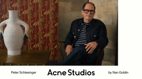 Peter Schlesinger seated in a dark denim jacket beside a white ceramic vessel for Acne Studios.