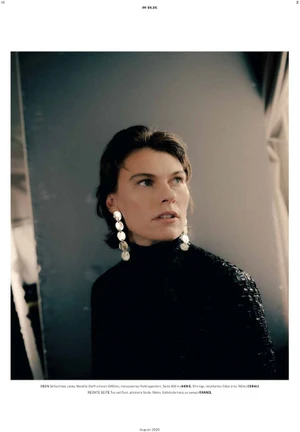 Model wearing a textured black turtleneck and dangling silver disc earrings looking to the side in a studio editorial.