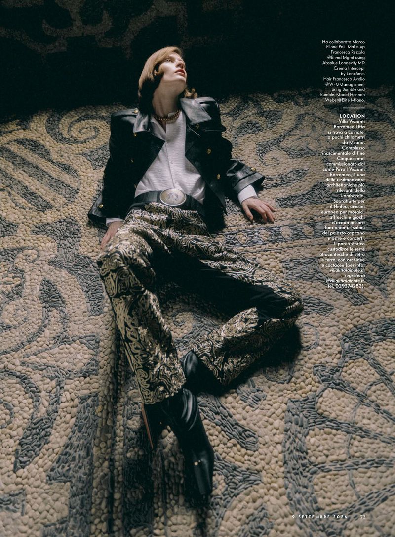 Model Hannah Weber reclines on an ornate stone mosaic floor in a black leather jacket, white shirt, and gold brocade trousers.