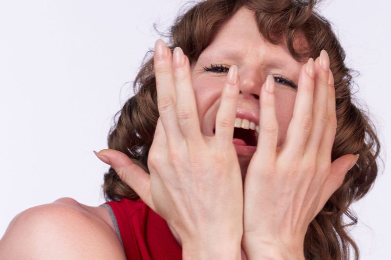 Larissa Moraes holds her hands to her face with an expressive open mouth in an editorial portrait for Pop Magazine.