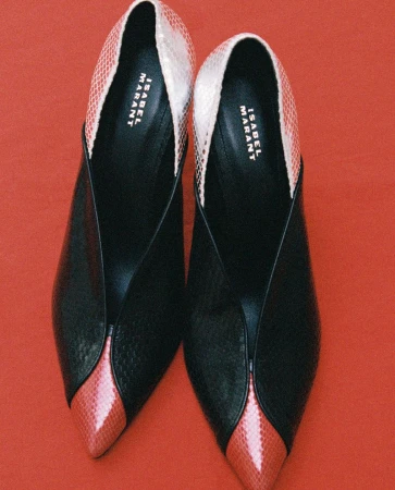 Pair of Isabel Marant pointed-toe black and coral pink snakeskin pumps arranged on a solid red background.