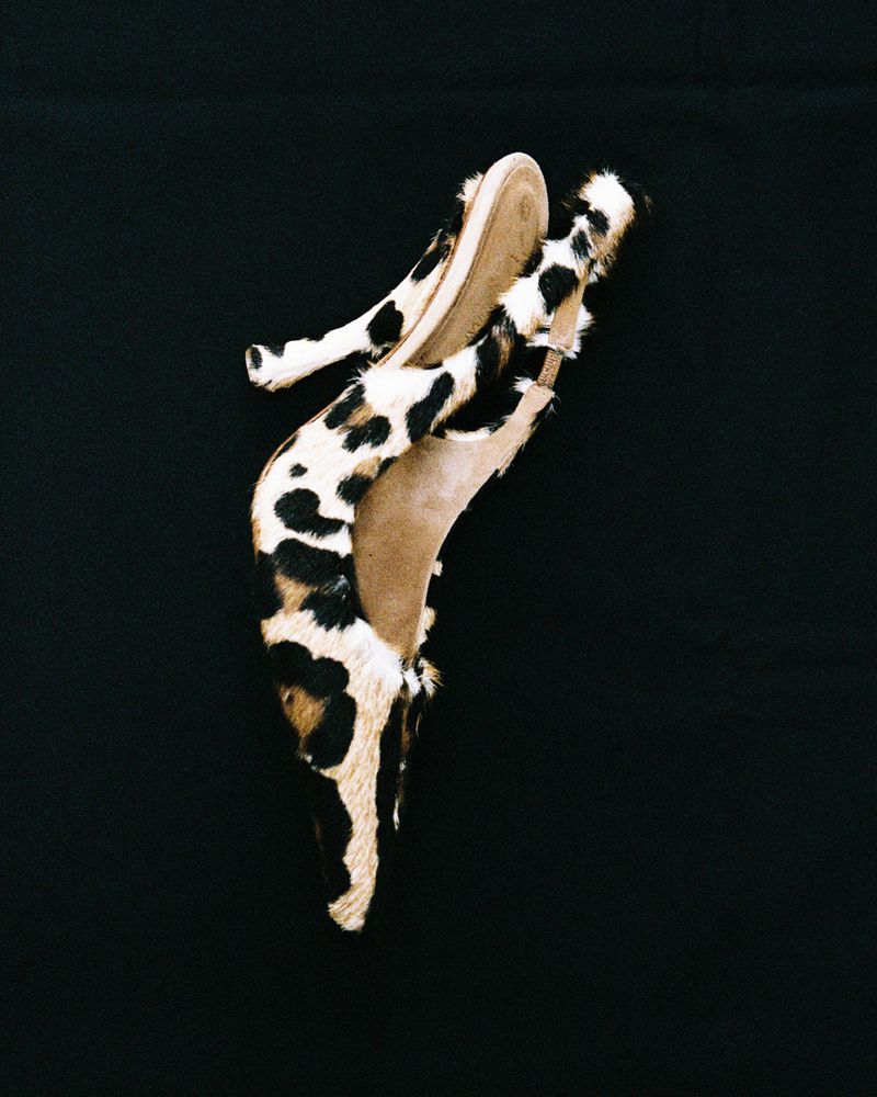 Spotted calf hair pointed-toe slingback high heels arranged vertically against a plain black background.