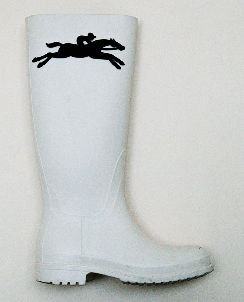 White rubber rain boot featuring a black horse and rider silhouette graphic against a plain white background.