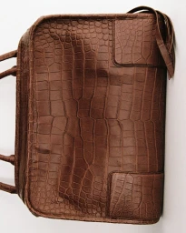 Brown crocodile-embossed leather handbag featuring top handles against a plain bright background.