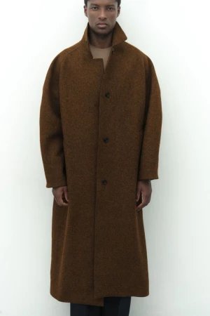 Model Aboubakar Konte wearing an oversized textured brown wool coat against a plain white studio background.