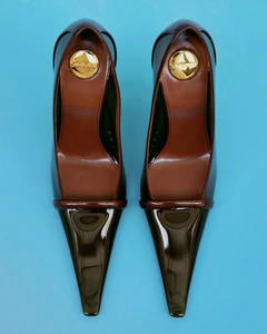 Top-down view of a pair of brown glossy pointed-toe high heel shoes placed symmetrically against a vibrant blue background.