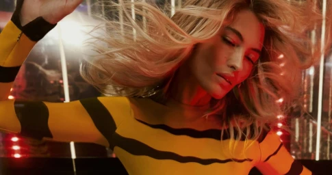 Model Grace Elizabeth in a yellow and black striped top with blonde hair whipping in motion for Emilio Pucci