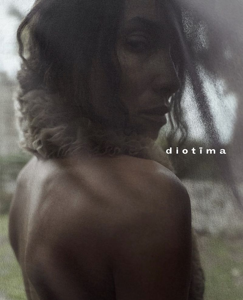 Close-up portrait of model Romae Gordon looking over a bare shoulder with textured grain for the Diotima campaign.