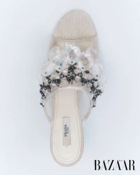 Top-down view of an embellished beige Prada mule sandal with faceted crystal clusters against a white studio background.