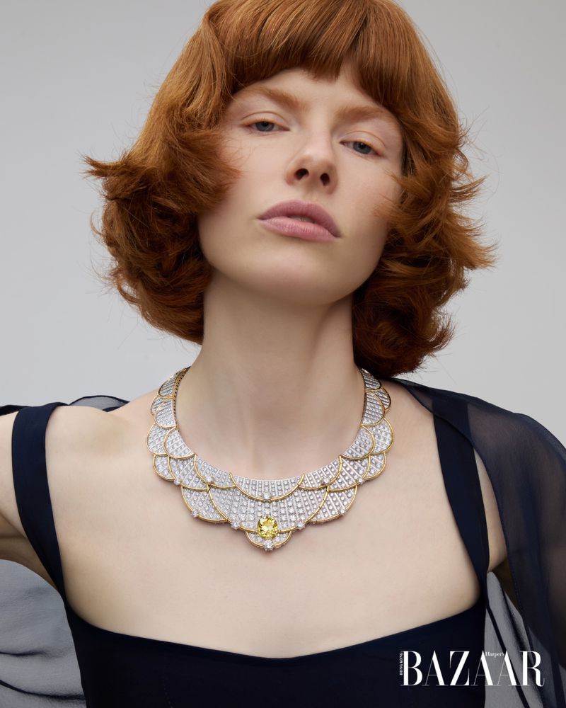 Edwina Preston wearing an elaborate scalloped diamond necklace and a black dress against a light grey studio background.