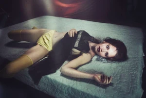 Model Arina Maksimova lying on a mattress wearing yellow lingerie and a sheer black top for The Perfect Magazine.