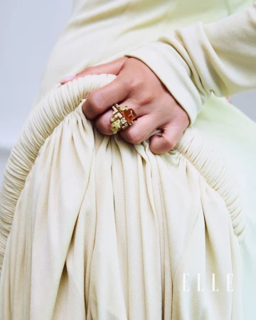 Model wearing a chunky gold cocktail ring with an amber stone while holding gathered cream fabric for Elle Türkiye.