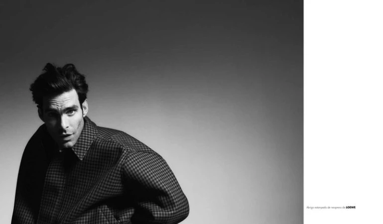 Model Jon Kortajarena posing in a houndstooth checkered jacket in a black and white fashion portrait.