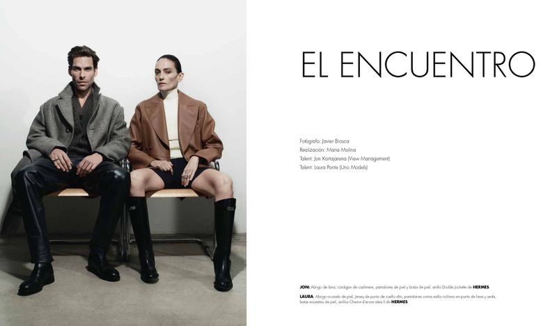 Jon Kortajarena and Laura Ponte seated side by side in tailored coats and boots for an El Encuentro fashion editorial layout.