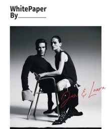 Jon Kortajarena and Laura Ponte posed together on a metal frame chair against a studio backdrop in black clothing.
