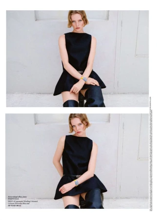 Model Maya Vozhdaeva in a black sleeveless mini dress and black thigh-high boots seated against a pale textured wall.