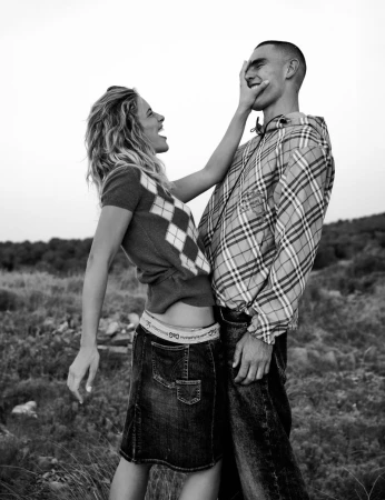 A woman in an argyle sweater playfully covering the face of model Josh McGregor wearing a plaid jacket in black and white.