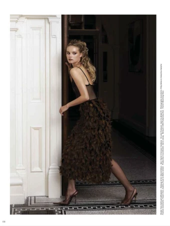 Model Tara Halliwell in a textured brown midi skirt and sheer black top looking back in a doorway for Vogue Hong Kong.