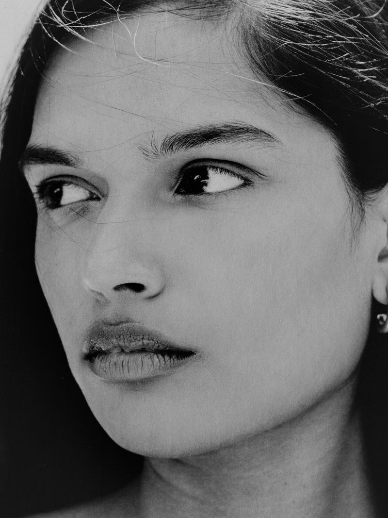 Black and white close-up portrait of model Selina Pillay with windblown hair looking to the side against a dark background.