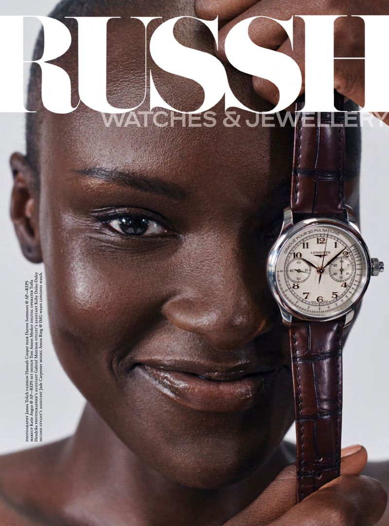 Amou Ring holding a Longines chronograph watch with a brown leather strap next to her face for Russh magazine.