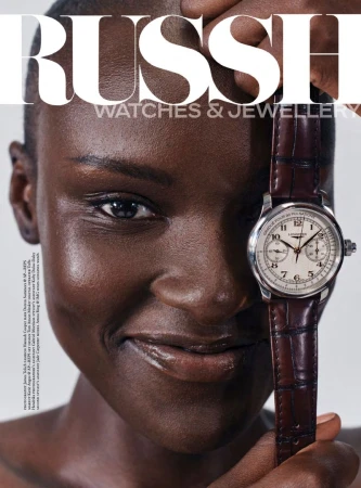 Amou Ring holding a Longines chronograph watch with a brown leather strap next to her face for Russh magazine.