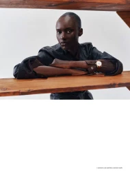 Model Amou Ring leaning on wooden planks wearing a dark jacket and wristwatch in an editorial portrait for Russh.