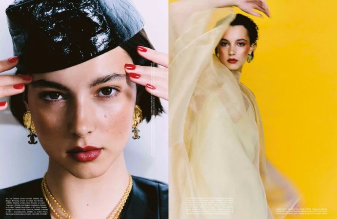 Editorial fashion close-up of a female model with red lipstick, wearing a black hat and jewelry, and a woman in yellow sheer clothing.