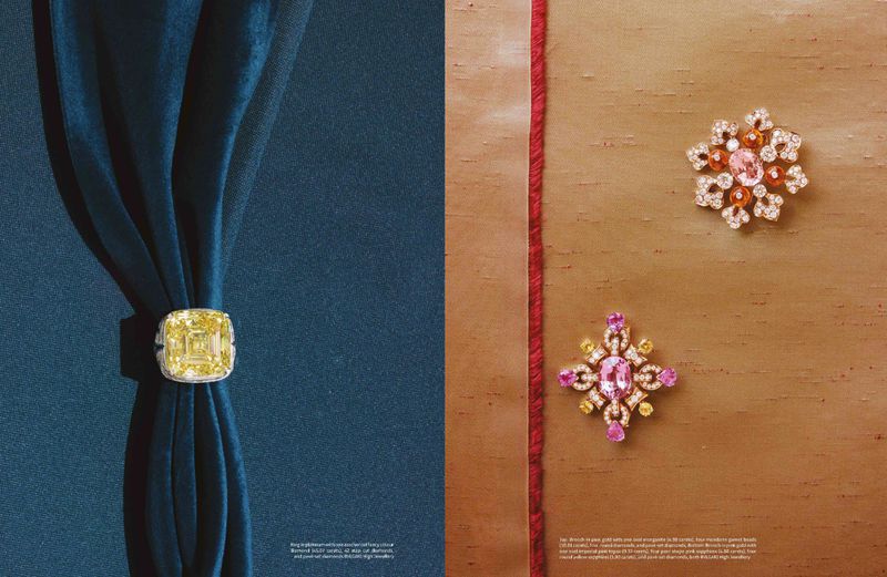Elegant jewelry display featuring a yellow diamond ring on teal fabric and snowflake brooches on textured tan fabric.
